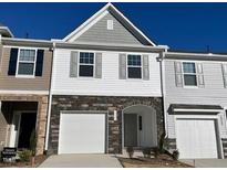 Two-story townhome with gray siding, stone accents, and a two-car garage at 838 Windmill Palm Dr, Zebulon, NC 27597