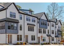 Modern townhouse complex showcasing white siding, black trim, and well-manicured landscaping at 6402 Tanner Oak Ln, Raleigh, NC 27613