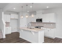 Bright kitchen features white cabinets, granite countertops, stainless appliances, and pendant lighting at 22 Van Winkle St, Lillington, NC 27546