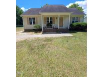 Charming single-story home featuring a welcoming porch, complemented by green lawns and inviting curb appeal at 310 E Horton St, Zebulon, NC 27597
