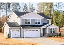 Two-story home with gray siding, black roof, three-car garage, and stone veneer accents at 7404 Prato Ct, Wendell, NC 27591