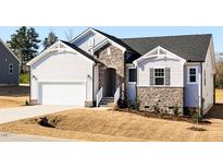 Charming home featuring stone accents, white siding, an attached garage, and fresh landscaping at 472 Barbour Farm Ln, Four Oaks, NC 27524