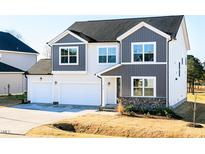 Charming two-story home with gray and white siding, a two-car garage, and a well-manicured lawn at 674 Barbour Farm Ln, Four Oaks, NC 27524