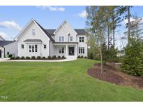 Elegant, modern two-story home featuring white brick, black roof, and lush green lawn at 2506 Silas Peak Ln, Apex, NC 27523