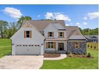 Charming two-story home featuring a white facade, stone accents, wooden shutters, and a neatly manicured lawn at 2568 Lassiter Rd, Four Oaks, NC 27524