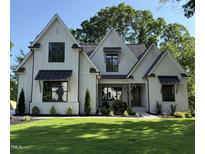 Charming two-story home boasts a modern farmhouse design, complemented by a lush green lawn and manicured landscaping at 4800 Lakemont Dr, Raleigh, NC 27609
