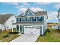 Charming two-story home featuring blue siding, black shutters and a two-car garage at 8905 Stratus St, Willow Springs, NC 27592