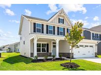 Charming two-story home with a manicured lawn, two-car garage, and a welcoming front porch at 8869 Tartan Clan Dr, Willow Springs, NC 27592