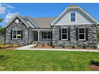 Charming stone-accented home with well-manicured lawn, sidewalk, and inviting covered porch at 135 Ironwood Blvd # 49, Youngsville, NC 27596