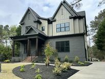 Elegant two-story home with a modern design, lush landscaping, and a gray brick and panel exterior at 14020 Durant Rd, Raleigh, NC 27614