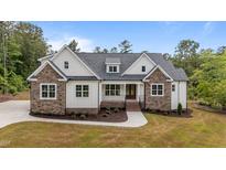Charming two-story home with stone and white siding, complemented by a lush, landscaped front yard at 225 Whistlers Cv, Louisburg, NC 27549