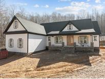Stunning white farmhouse with a dark roof, welcoming porch, and stone accents at 2817 Silk Hope Gum Springs Rd, Pittsboro, NC 27312