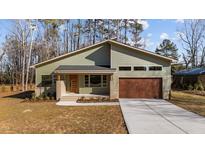 Modern house with green siding, brown garage door, and a landscaped yard at 5300 Pulley Town Rd, Zebulon, NC 27597