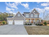 Charming two-story home with gray siding, a three-car garage, and a welcoming front porch at 649 Riverwood Dr, Clayton, NC 27527
