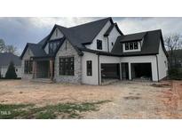 A modern farmhouse with stone accents, black trim, white siding, and a two-car garage under construction at 126 Harvest Ln, Pittsboro, NC 27312