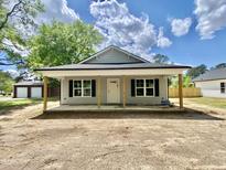 Charming single-story home with a covered front porch, black shutters, and gray siding offers a welcoming facade at 233 Jenkins St, Erwin, NC 28334