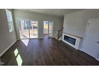 Bright living room with dark floors, sliding glass doors, and modern fireplace at 1349 Bessie Ct, Wake Forest, NC 27587
