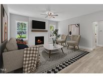 Inviting living room featuring a cozy fireplace, stylish decor, and hardwood flooring at 119 Water Ave, Wake Forest, NC 27587