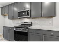 Well-equipped kitchen features gray cabinets, stainless steel appliances, and elegant white countertops and backsplash at 484 Traditions Grande Blvd # 29, Wake Forest, NC 27587