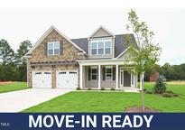Move-in ready two-story house with stone and siding, two-car garage, and landscaped lawn at 138 Abingdon Farms Dr, Selma, NC 27576