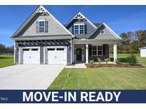 Move-in ready two-story home with gray siding, two-car garage, and landscaped lawn at 76 Abingdon Farms Dr, Selma, NC 27576