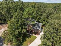 An aerial view of a brick home featuring a large lot surrounded by mature trees and a long driveway at 111 N Coslett Ct, Cary, NC 27513