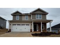 Two-story home with a two-car garage, beige siding, and a stone accent under a cloudy sky at 42 Decatur Dr, Fuquay Varina, NC 27526