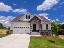 Charming home featuring a stone archway, two-car garage, and a well-manicured lawn at 85 Claude Creek Way, Smithfield, NC 27577