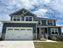 Two-story home featuring a two-car garage and a combination of stone and blue siding at 499 Glenkirk Pl # 101, Garner, NC 27529