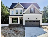 Charming two-story home showcasing a gray garage, brick accents, and light gray siding under a clear blue sky at 2617 Silver Gate Ct, Wake Forest, NC 27587
