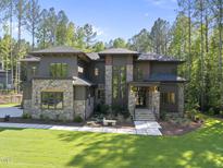 Stunning home featuring a stone and modern facade, professional landscaping, and a welcoming entrance at 7640 Falls Creek Ln, Raleigh, NC 27614