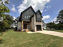 Charming two-story home featuring a brick facade, black trim, manicured lawn, and a two-car garage at 627 Georgetown Rd, Raleigh, NC 27608