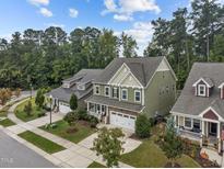 Charming homes featuring well-manicured lawns, attached garages, and beautifully designed facades, surrounded by lush trees at 609 Meadowgrass Ln, Wake Forest, NC 27587