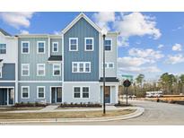 Charming new construction townhome with blue accents and inviting curb appeal on a sunny day at 1170 Holding Village Way, Wake Forest, NC 27587