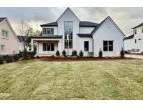 Two-story white brick home with a large front yard and landscaping at 3407 Churchill Rd, Raleigh, NC 27607