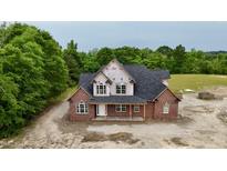New two-story brick home with a dark roof and covered porch nestled on a wooded lot at 6352 River Rd, Fuquay Varina, NC 27526
