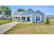 Charming blue home featuring a covered entrance, well-manicured lawn, and inviting curb appeal at 306 E Godwin St, Dunn, NC 28334