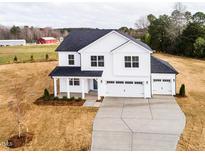 New construction home with a three-car garage, white siding, dark roof, and covered porch at 7417 Prato Ct, Wendell, NC 27591