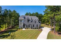 Beautiful gray brick home featuring a manicured lawn, long driveway, and tall trees, creating a serene and private setting at 162 Seaforth Preserve Dr, Pittsboro, NC 27312