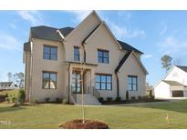 Charming two-story home with a brick exterior, black roof, manicured lawn, and well-lit entryway at 2525 Silas Peak Ln, Apex, NC 27523