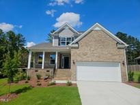 Two-story brick and siding home with manicured lawn, garage, and inviting front porch at 145 Green Haven Blvd # 83, Youngsville, NC 27596