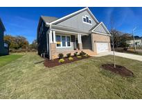 Charming two-story home featuring a brick and gray siding exterior, manicured lawn, and inviting front porch at 1504 Maelyn Way, Fuquay Varina, NC 27526