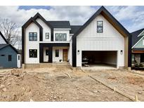 Modern farmhouse exterior with black trim, a two-car garage, and unfinished landscaping at 205 Red Cardinal Ct, Youngsville, NC 27596