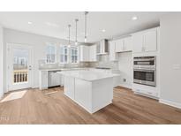 Bright kitchen features a large island, stainless appliances, and wood-look floors at 1206 Holding Village Way, Wake Forest, NC 27587