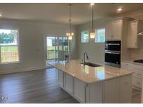 Modern kitchen features an island with white countertops and stainless steel appliances at 1528 Maelyn Way, Fuquay Varina, NC 27526