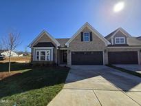 Charming new construction home boasts a brick facade, a two-car garage, and a well-manicured lawn at 2080 Harris Farm Ct, Burlington, NC 27215