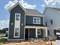 Stylish two-story home featuring modern vertical siding, white trim, and a welcoming front porch, still under construction at 2412 Adrift Road, Fuquay Varina, NC 27526