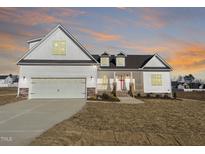 Two-story farmhouse with white siding, gray garage door, and stone accents at 119 Seahawk Way, Zebulon, NC 27597