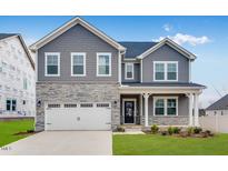 Beautiful two-story home featuring a stone facade, gray siding, a white garage door and a well-manicured lawn at 929 Kinglet House Rd, Knightdale, NC 27545