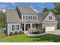 Charming two-story home with gray siding, stone accents, manicured lawn, and a welcoming front porch at 133 Synandra Ln, Holly Springs, NC 27540